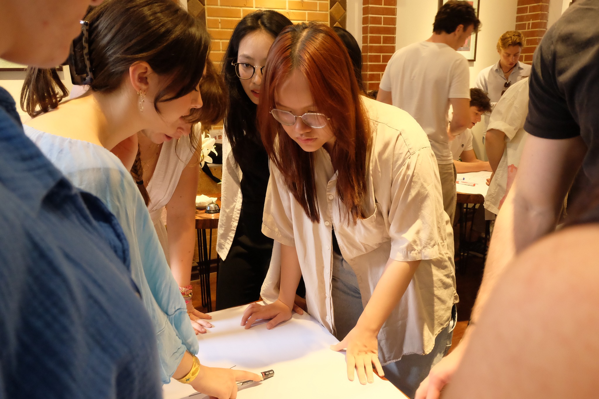 Diverse young students in a collaborative workshop inside a modern, light-filled academic space.